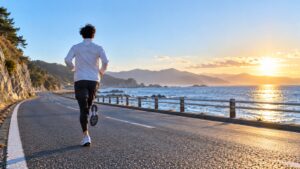 冬の朝、海沿いの道を走るランナー（イメージ）