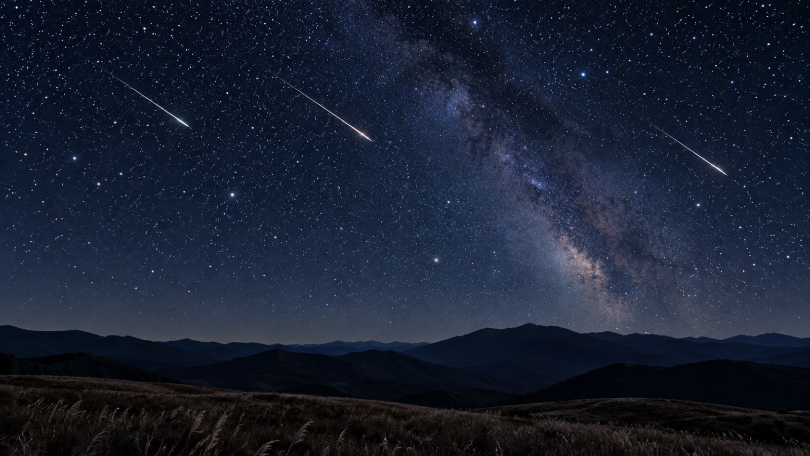 秋の夜空に流れる流れ星と山並み(イメージ)